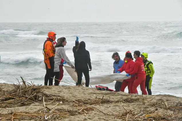 Rescuers recover a body after a migrant boat broke apart in rough seas, at a beach near Cutro, southern Italy, Sunday, Feb. 26, 2023. Rescue officials say an undetermined number of migrants have died and dozens have been rescued after their boat broke apart off southern Italy. (AP Photo/Giuseppe Pipita)