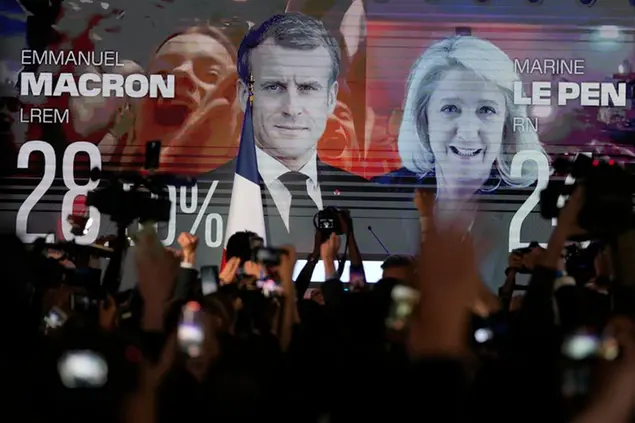 A screen shows French President Emmanuel Macron and centrist candidate for reelection and far-right candidate Marine Le Pen at her election day headquarters, in Paris, Sunday, April 10, 2022. French polling agency projections show incumbent French President Emmanuel Macron and far-right leader Marine Le Pen leading in the first round of France's presidential election Sunday. (AP Photo/Francois Mori)