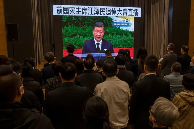 Residents watch a live broadcast of the memorial service for late former Chinese President Jiang Zemin where Chinese President Xi Jinping makes a speech on screen at a community center in Hong Kong, Tuesday, Dec. 6, 2022. A formal memorial service was held Tuesday at the Great Hall of the People, the seat of the ceremonial legislature in the center of Beijing. Words on screen read \\\"Former Chairman Jiang Zemin memorial live broadcast.\\\" (AP Photo/Vernon Yuen)