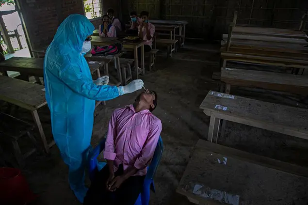 An Indian health worker takes a nasal swab sample of a student to test for coronavirus after classes started at a college in Jhargaon village, outskirts of Gauhati, India, Wednesday, Sept. 30, 2020. India's Health Ministry on Wednesday raised its confirmed total of coronavirus cases to more than 6.2 million. (AP Photo/Anupam Nath)