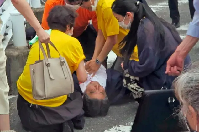 In this image from a video, Japan’s former Prime Minister Shinzo Abe, center, falls on the ground in Nara, western Japan Friday, July 8, 2022. Former Japanese Prime Minister Shinzo Abe, a divisive arch-conservative and one of his nation's most powerful and influential figures, has died after being shot during a campaign speech Friday in western Japan, hospital officials said.(Kyodo News via AP)