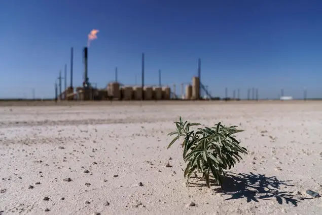 A lone plant grows from the dry soil next to a flare burning off methane and other hydrocarbons in the Permian Basin in Pecos, Texas, Wednesday, Oct. 13, 2021. The accumulation of carbon dioxide and methane in the blanket of gases encircling the Earth is holding more heat in. And there is now nearly three times as much methane in the air than there was before industrial times. The year 2021 saw the worst single increase ever. (AP Photo/David Goldman)