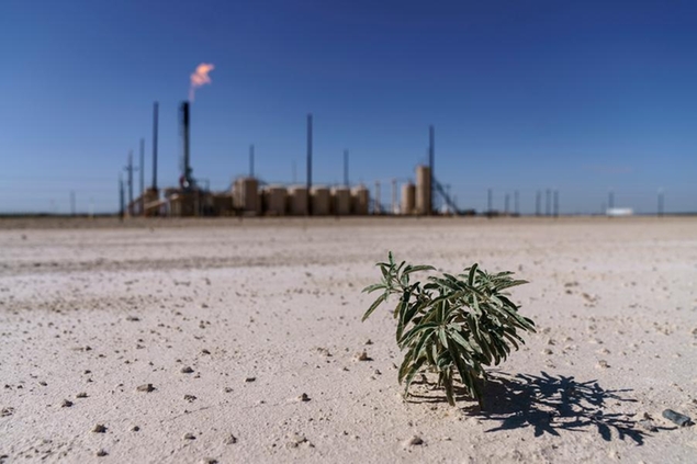 A lone plant grows from the dry soil next to a flare burning off methane and other hydrocarbons in the Permian Basin in Pecos, Texas, Wednesday, Oct. 13, 2021. The accumulation of carbon dioxide and methane in the blanket of gases encircling the Earth is holding more heat in. And there is now nearly three times as much methane in the air than there was before industrial times. The year 2021 saw the worst single increase ever. (AP Photo/David Goldman)