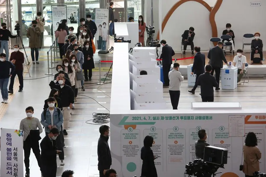 People wearing face masks line up to cast their early votes for the upcoming the Seoul mayoral by-election at a polling station in Seoul, South Korea, Friday, April 2, 2021. The early voting for the April 7 Seoul and Busan mayoral by-election will be held for two-days on April 2-3. (AP Photo/Ahn Young-joon)