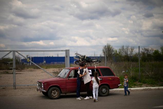 Orlyanske, left, hugs his wife Kolya next to their car as they arrive from Vasylivka to a reception center for displaced people in Zaporizhzhia, Ukraine, Tuesday, May 3, 2022. Thousands of Ukrainian continue to leave Russian occupied areas. (AP Photo/Francisco Seco)