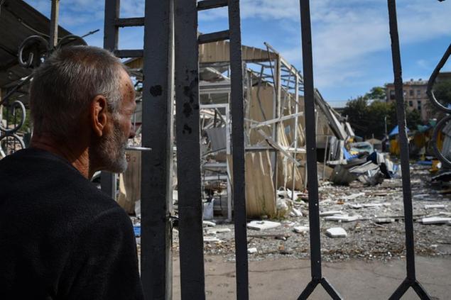A man stands in front of the gate of local market with heavily damaged shops after latest Russian rocket attack in Dnipro, Ukraine, Monday, Sept. 12, 2022. (AP Photo/Andriy Andriyenko)