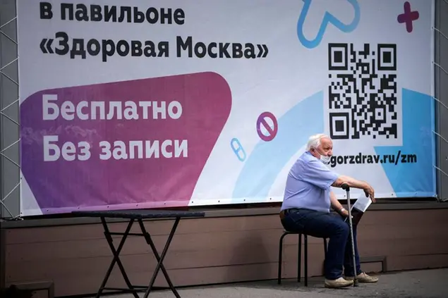An elderly man sits waiting in line to get a coronavirus vaccine at a vaccination center at VDNKh (The Exhibition of Achievements of National Economy) in Moscow, Russia\\u00A0(AP Photo/Alexander Zemlianichenko)