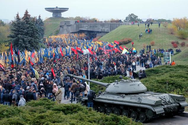 FILE - Volunteers of the Azov Civil Corps pass by a tank in a WWII memorial at a rally marking Fatherland Defender Day in Kyiv, Ukraine, on Oct. 14, 2016. The Ukrainian forces who made a determined last stand in a Mariupol steel mill against Russian troops were a mixture of seasoned soldiers, border guards, a controversial national guard regiment and volunteers who took up arms in the weeks before Russia's invasion. (AP Photo/Efrem Lukatsky, File)