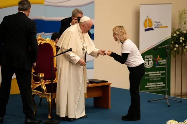 Pope Francis gives a gift to a youth during his visit at the Saint Dionysius School of the Ursuline Sisters in Athens, Greece, Monday, Dec. 6, 2021. Francis' five-day trip to Cyprus and Greece has been dominated by the migrant issue and Francis' call for European countries to stop building walls, stoking fears and shutting out \\\"those in greater need who knock at our door.\\\" (AP Photo/Thanassis Stavrakis, Pool)
