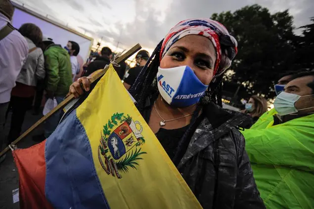 A Venezuelan migrant poses for a photo with her country\\\\'s flag while attending a campaign rally for Chilean Republican Party presidential candidate Jose Antonio Kast, in Valdivia, Chile, Wednesday, Nov. 17, 2021. Chile will hold its presidential election on Nov. 21. (AP Photo/Jose Luis Saavedra)