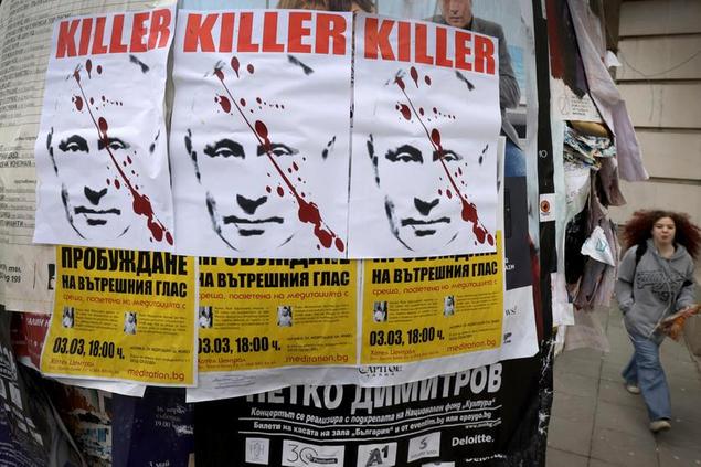 A woman passes by posters depicting Russian President Vladimir Putin with a sign \\\\\\\"Killer\\\\\\\" seen in downtown Sofia Thursday, Feb. 24, 2022. The posters appeared on the day Russia started military operation against Ukraine. (AP Photo/Valentina Petrova)