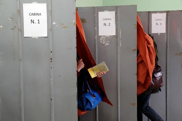 A woman gets out of a voting booth at a polling station in Fiuggi, Italy, Sunday, March 4, 2018. More than 46 million Italians were voting Sunday in a general election that is being closely watched to determine if Italy would succumb to the populist, anti-establishment and far-right sentiment that has swept through much of Europe in recent years. (AP Photo/Gregorio Borgia)