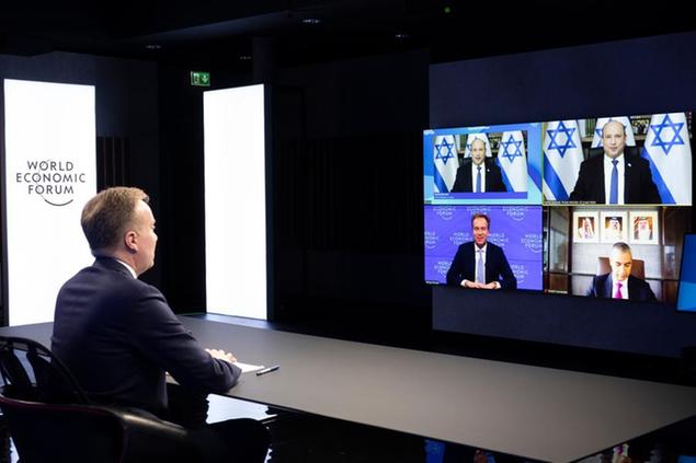 Norwegian Borge Brende, left, President of the World Economic Forum,WEF, listens Israeli Prime Minister Naftali Bennet, top in screen, during the Davos Agenda 2022 online meeting, in Cologny near Geneva, Switzerland, Tuesday, Jan. 18, 2022. The Davos Agenda, from Jan. 17 to Jan. 21, 2022, is an online edition of the annual meeting of the WEF due to the coronavirus pandemic. (Salvatore Di Nolfi/Keystone via AP)