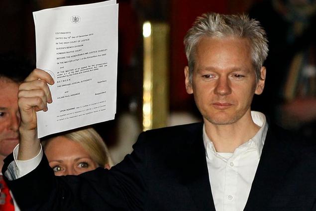 FILE - In this Thursday, Dec. 16, 2010 file photo, WikiLeaks founder Julian Assange holds up a court document for the media after he was released on bail, outside the High Court in London. WikiLeaks founder Julian Assange will find out Monday Jan. 4, 2021 whether he can be extradited from the U.K. to the U.S. to face espionage charges over the publication of secret American military documents. (AP Photo/Kirsty Wigglesworth, file)