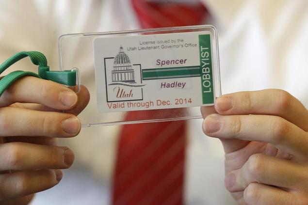 In this Thursday, July 31, 2014, photo, a staff member at the Utah lieutenant governor's office holds a sample badge lobbyists will be required to wear at the state Capitol after Aug. 1, at the Utah State Capitol, in Salt Lake City. Fourteen other states require lobbyists to wear badges. (AP Photo/Rick Bowmer)