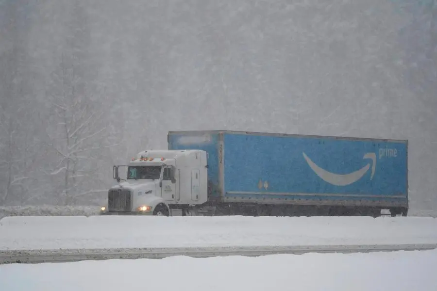 An Amazon.com truck drives on a snow-covered stretch of westbound Interstate Highway 90, Thursday, Dec. 9, 2021, as snow falls near Snoqualmie Pass in Washington state. More U.S. drivers could find themselves stuck on snowy highways or have their travel delayed this winter due to a shortage of snowplow drivers as some states are having trouble finding enough people willing to take the jobs. (AP Photo/Ted S. Warren)