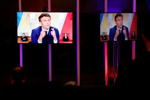 People watch centrist candidate and French President Emmanuel Macron durng his televised debate against far-right contender Marine Le Pen in La Plaine-Saint-Denis, outside Paris, Wednesday, April 20, 2022. In the climax of France's presidential campaign, centrist President Emmanuel Macron and far-right contender Marine Le Pen meet Wednesday evening in a one-on-one television debate that could prove decisive before Sunday's runoff vote. (Ludovic Marin, Pool via AP)