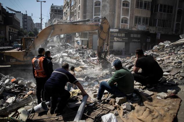 Palestinian rescuers search for survivors under the rubble of destroyed residential buildings following deadly Israeli airstrikes in Gaza City, Sunday, May 16, 2021. The airstrikes flattened three buildings and killed at least 26 people Sunday, medics said, making it the deadliest single attack since heavy fighting broke out between Israel and the territory's militant Hamas rulers nearly a week ago. (AP Photo/Khalil Hamra)