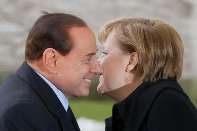 German Chancellor Angela Merkel, right, and Italian Prime Minister Silvio Berlusconi kiss each other before the welcoming ceremony with military honors in front of the chancellery in Berlin, Germany, Wednesday, Jan. 12, 2011. (AP Photo/Gero Breloer)