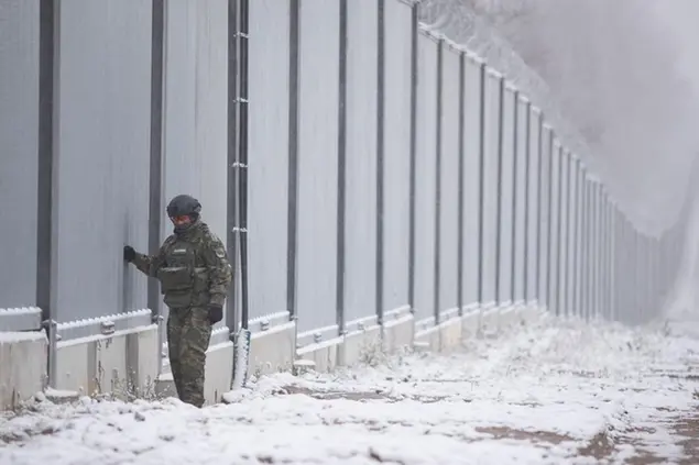 Polish border guard stands next to the border wall in Nomiki, Poland, Friday Nov, 2022. Polandâ€™s Interior Minister and the head of the Border Guard marked the completion Friday of the first part of electronic monitoring on Polandâ€™s metal wall with Belarus built this year to stop thousands of migrants - pushed by Minsk authorities - from crossing into the European Union. (AP Photo/Maciek Luczniewski)
