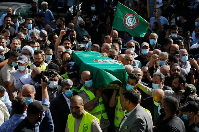 Supporters of the Shiite Amal group carry the coffin of Hassan Jamil Nehmeh, who was killed during yesterday clashes, during his funeral processions in the southern Beirut suburb of Dahiyeh, Lebanon, Friday, Oct. 15, 2021. The government called for a day of mourning following the armed clashes, in which gunmen used automatic weapons and rocket-propelled grenades on the streets of the capital, echoing the nation’s darkest era of the 1975-90 civil war. (AP Photo/Bilal Hussein)