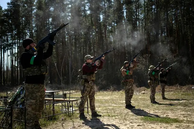 Ukrainian soldiers perform a rifle volley during the funeral of Anatoliy Kolesnikov, 30, and Oleksandr Mozheiko, 31, both territorial defense soldiers who were killed by Russian, in Irpin, in the outskirts of Kyiv, Ukraine, Friday, April 15, 2022. (AP Photo/Rodrigo Abd)