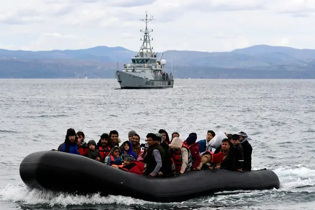 Migrants arrive with a dinghy accompanied by a Frontex vessel at the village of Skala Sikaminias, on the Greek island of Lesbos, after crossing the Aegean sea from Turkey, on Feb. 28, 2020. AP