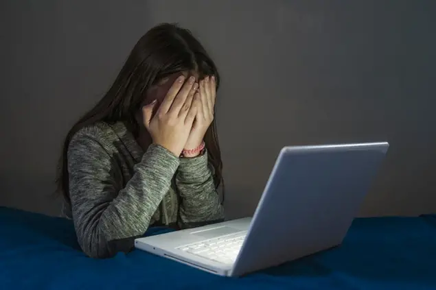 Teenager girl suffering internet cyber bullying scared and depressed cyberbullying. Image of despair girl humilated on internet by classmate. Young teenage girl crying in front of the laptop