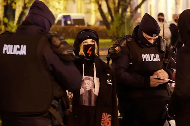 (La polizia chiede i documenti a una attivista durante una protesta\\u00A0a Varsavia il 6 novembre. Foto LaPresse)