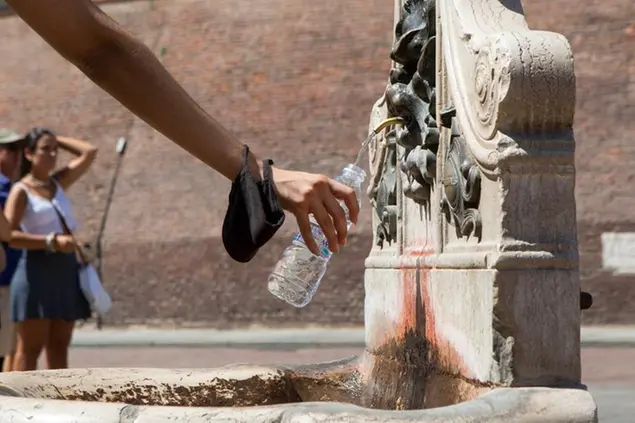 A Bologna turisti si rinfrescano alla fontana del Nettuno (LaPresse)