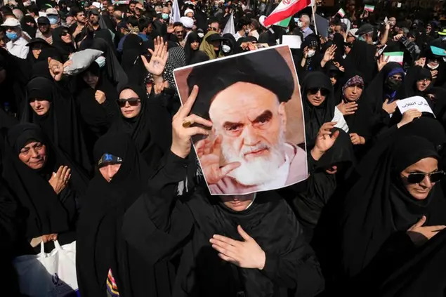 A pro-government demonstrator holds a poster of the late Iranian revolutionary founder Ayatollah Khomeini while attending a rally after the Friday prayers to condemn recent anti-government protests over the death of a young woman in police custody, in Tehran, Iran, Friday, Sept. 23, 2022. The crisis unfolding in Iran began as a public outpouring over the the death of Mahsa Amini, a young woman from a northwestern Kurdish town who was arrested by the country's morality police in Tehran last week for allegedly violating its strictly-enforced dress code. (AP Photo/Vahid Salemi)