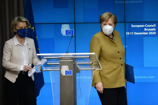 German Chancellor Angela Merkel, right, and European Commission President Ursula von der Leyen arrive for a media conference at an EU summit in Brussels, Friday, Dec. 11, 2020. European Union leaders have reached a hard-fought deal to cut the bloc's greenhouse gas emissions by at least 55 percent by the end of the decade compared with 1990 levels, avoiding a hugely embarrassing deadlock ahead of a U.N. climate meeting this weekend. (Johanna Geron, Pool via AP)