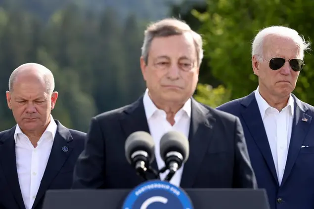 German Chancellor Olaf Scholz and U.S. President Joe Biden stand behind Italian Prime Minister Mario Draghi as he speaks, on the first day of the G7 leaders' summit, at Bavaria's Schloss Elmau castle, in Kruen, Germany, Sunday, June 26, 2022. (Lukas Barth/Pool Photo via AP)