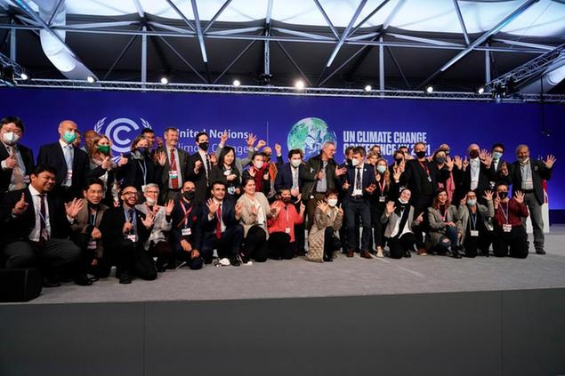 Delegates from different countries pose for a group photograph together on stage in the plenary room at the COP26 U.N. Climate Summit, in Glasgow, Scotland, Saturday, Nov. 13, 2021. Going into overtime, negotiators at U.N. climate talks in Glasgow are still trying to find common ground on phasing out coal, when nations need to update their emission-cutting pledges and, especially, on money. (AP Photo/Alberto Pezzali)