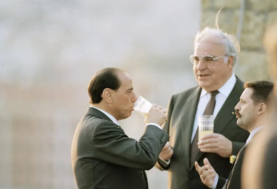Italian Premier Silvio Berlusconi, left, and German Chancellor Helmut Kohl chat during the first meeting of the leaders of the most industrialized countries at Castle dell’Ovo in Naples, Italy on Friday, July 8, 1994. The annual economic G7 summit started on Friday at night in Naples. Man at right unidentified. (AP Photo/Martin Cleaver)