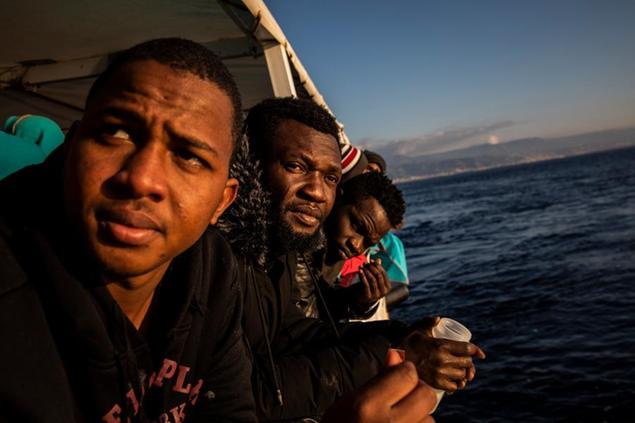 Nigerian men who were rescued off the Libyan coast on Friday, watch the sea from the deck of the Open Arms rescue vessel as the ship approaches the port of Messina, Italy, Wednesday, Jan. 15, 2020. (AP Photo/Santi Palacios)