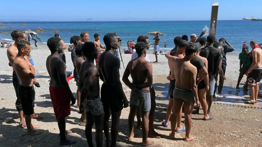 Una barca carica di migranti si avvicina alla costa di Formentera, con un elicottero che sorvola la scena