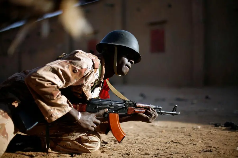 A Malian soldier takes cover behind a truck during exchanges of fire with jihadists in Gao, northern Mali, Sunday, Feb. 10, 2013. (AP Photo/Jerome Delay)