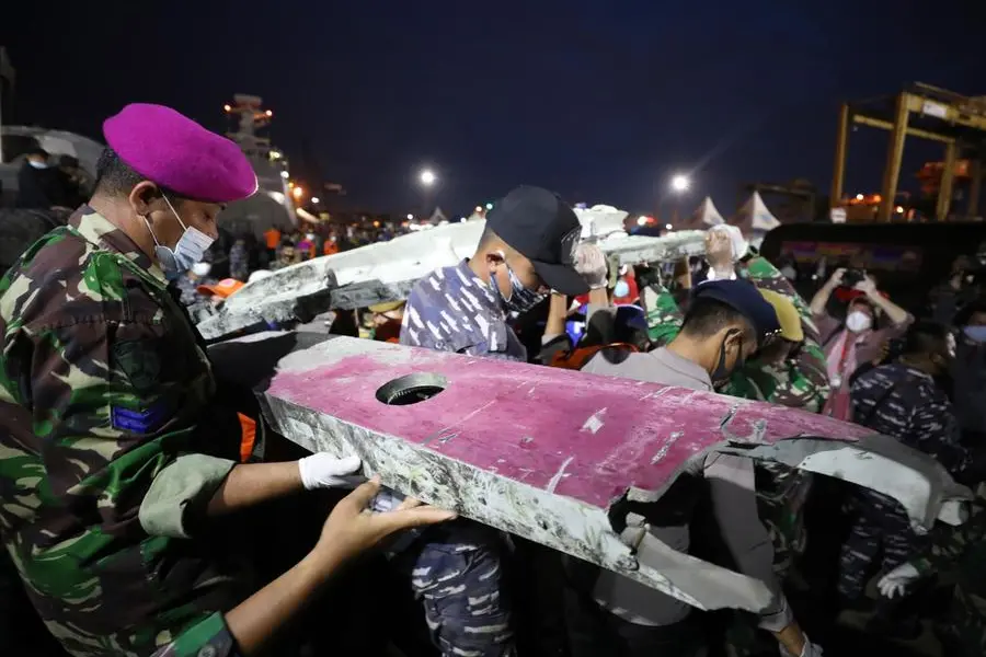 Soldiers and rescue personnel carry debris found in the waters off Java Island around where a Sriwijaya Air passenger jet crashed on Saturday, at Tanjung Priok Port in Jakarta, Indonesia, Sunday, Jan. 10, 2021. Indonesian rescuers pulled out body parts, pieces of clothing and scraps of metal from the Java Sea early Sunday morning, a day after a Boeing 737-500 with dozens of people onboard crashed shortly after takeoff from Jakarta, officials said. (AP Photo/Dita Alangkara)
