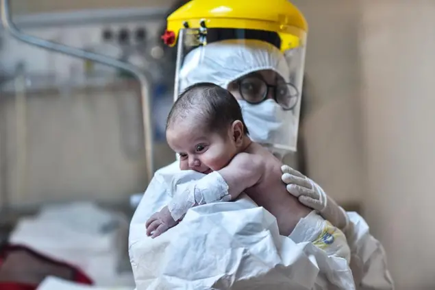 In this Monday, May 11, 2020 photo, a nurse, wearing a face mask and a shield to protect against coronavirus, carries baby Amine Tepe who was infected with COVID-19, as she is taken out of the intensive care unit following a week's treatment, at an Istanbul hospital. Tepe was diagnosed with coronavirus when she was 37 days old after contracting the virus from her parents according to doctors. The baby has been moved to a hospital ward. Turkey's government announced a \\\"normalization plan\\\" as the number of new virus cases declined last week but warned of tougher measures, if infections go up again. (Ibrahim Mase/DHA via AP)