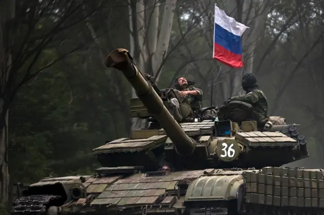 FILE - A pro-Russian rebel looks up while riding on a tank flying Russia's flag, on a road east of Donetsk, eastern Ukraine, July 29, 2015. Amid fears of a Russian invasion of Ukraine, tensions have also soared in the countryâ€™s east, where Ukrainian forces are locked in a nearly eight-year conflict with Russia-backed separatists. A sharp increase in skirmishes on Thursday raised fears that Moscow could use the situation as a pretext for an incursion. (AP Photo/Vadim Ghirda, File)