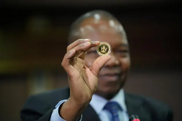 Reserve Bank of Zimbabwe Governor, John Mangudya holds a sample of a gold coin at the launch in Harare, Monday, July, 25, 2022.Zimbabwe has launched gold coins to be sold to the public in a bid to to tame runaway inflation that has further eroded the country's unstable currency. (AP Photo/Tsvangirayi Mukwazhi)