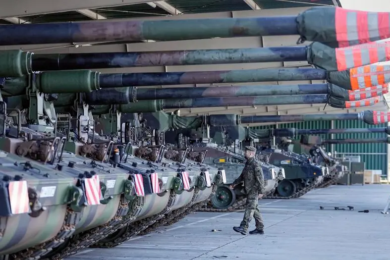 German soldiers walk beside tank howitzers prior transport to Lithuania at the Bundeswehr army base in Munster, northern Germany, Monday, Feb. 14, 2022. Germany gears up the Enhanced Forward Presence Battle Group in Lithuania at the NATO eastern front. (AP Photo/Martin Meissner)