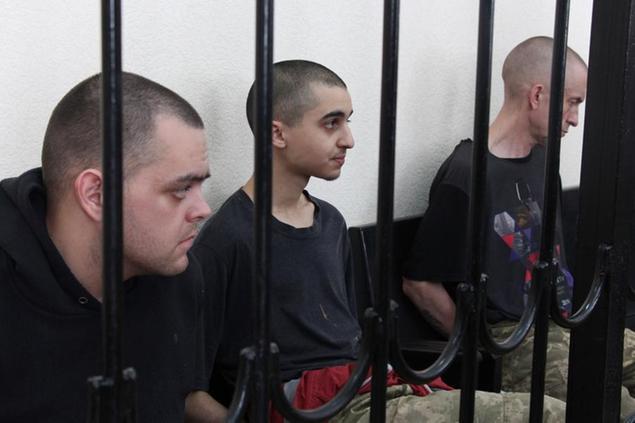 Two British citizens Aiden Aslin, left, and Shaun Pinner, right, and Moroccan Saaudun Brahim, center, sit behind bars in a courtroom in Donetsk, in the territory which is under the Government of the Donetsk People's Republic control, eastern Ukraine, Thursday, June 9, 2022. The two British citizens and a Moroccan have been sentenced to death by pro-Moscow rebels in eastern Ukraine for fighting on Ukraine's side. The three men fought alongside Ukrainian troops and surrendered to Russian forces weeks ago. (AP Photo)