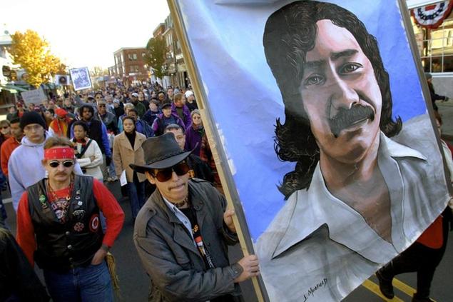 FILE - In this Nov. 22, 2001, file photo, marchers carry a large painting of jailed American Indian Leonard Peltier during a march for the National Day of Mourning in Plymouth, Mass. United American Indians of New England held its first National Day of Mourning in 1970. Tribes again plan to gather at noon on a windswept hill overlooking Plymouth Rock on Thanksgiving Day, Thursday, Nov. 28, 2019. (AP Photo/Steven Senne, File)