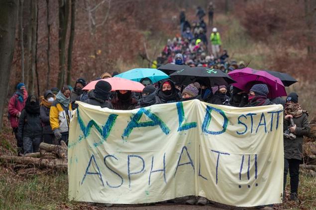 29 November 2020, Hessen, Dannenrod: Several hundreds of activists march behind a banner with the inscription \\\"Forest instead of asphalt!!!\\\" through the forest towards the clearing lane. Environmental and climate protectors have been protesting for months in the Dannenr'der Forest against the controversial further construction of the Autobahn 49. Photo by: Boris Roessler/picture-alliance/dpa/AP Images