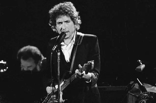 FILE - Musician Bob Dylan performs with The Band at the Forum in Los Angeles on Feb. 15, 1974. Transcripts of lost 1971 Dylan interviews with the late American blues artist Tony Glover and letters the two exchanged reveal that Dylan changed his name from Robert Zimmerman because he worried about anti-Semitism, and that he wrote \\\"Lay Lady Lay\\\" for actress Barbra Streisand. The items are among a trove of Dylan archives being auctioned in November 2020 by Boston-based R.R. Auction. (AP Photo/Jeff Robbins, File)