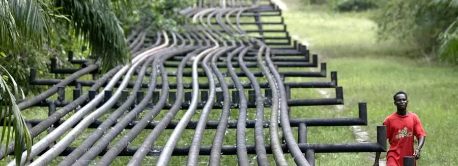 An unidentified man walks along oil pipelines belonging to Agip Oil company in Obrikom, Nigeria, Monday, March 6, 2006. Armed militants in Nigeria vowed Sunday to cut daily oil exports from this West African nation's troubled delta region by another 1 million barrels by the end of March, as OPEC nations prepared for a strategy meeting in Vienna this week. A wave of militant assaults on pipelines and oil facilities has already cut production by 455,000 barrels per day in Nigeria, which normally exports 2.5 million barrels of crude daily. (AP Photo/George Osodi)