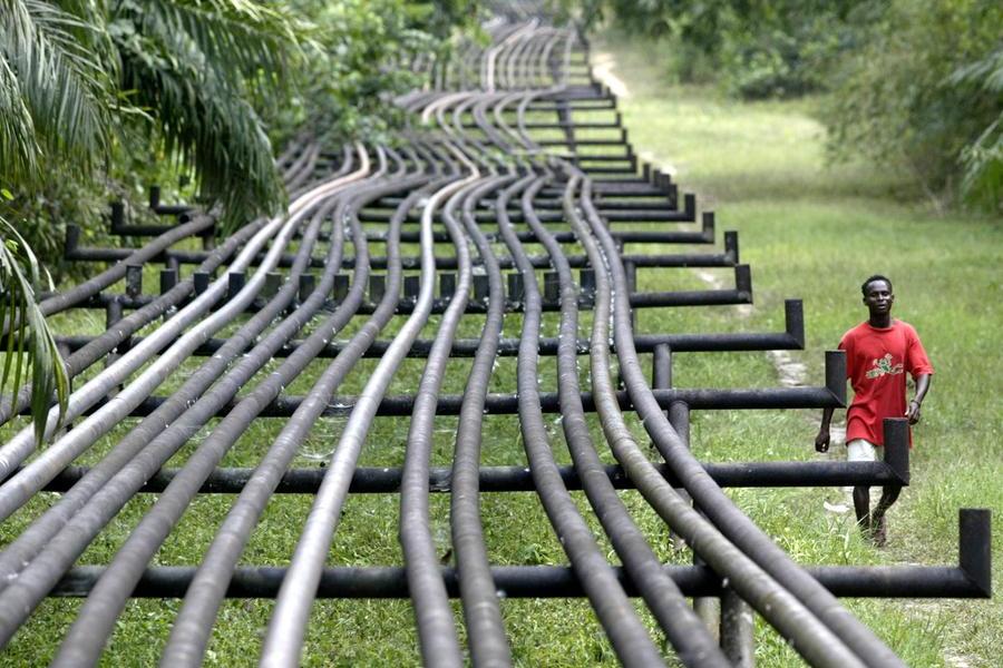 An unidentified man walks along oil pipelines belonging to Agip Oil company in Obrikom, Nigeria, Monday, March 6, 2006. Armed militants in Nigeria vowed Sunday to cut daily oil exports from this West African nation's troubled delta region by another 1 million barrels by the end of March, as OPEC nations prepared for a strategy meeting in Vienna this week. A wave of militant assaults on pipelines and oil facilities has already cut production by 455,000 barrels per day in Nigeria, which normally exports 2.5 million barrels of crude daily. (AP Photo/George Osodi)