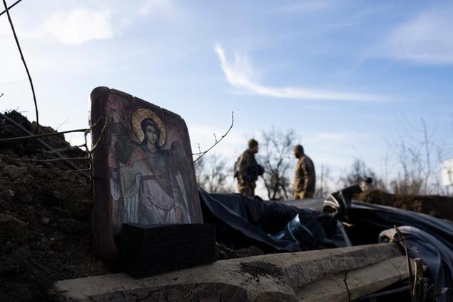 The icon of Archagelos Michael stands on an army trench as you Ukranian soldier are seen in the background, in the outskirts of Mykolaiv, Ukraine, Saturday, March 26, 2022.(AP Photo/Petros Giannakouris)